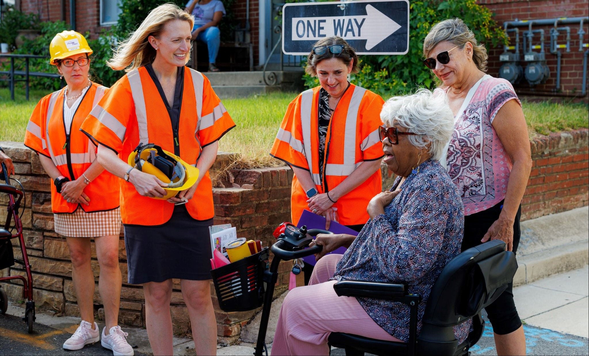 Comptroller Lierman wearing a construction vest, talking with a small group of people outside