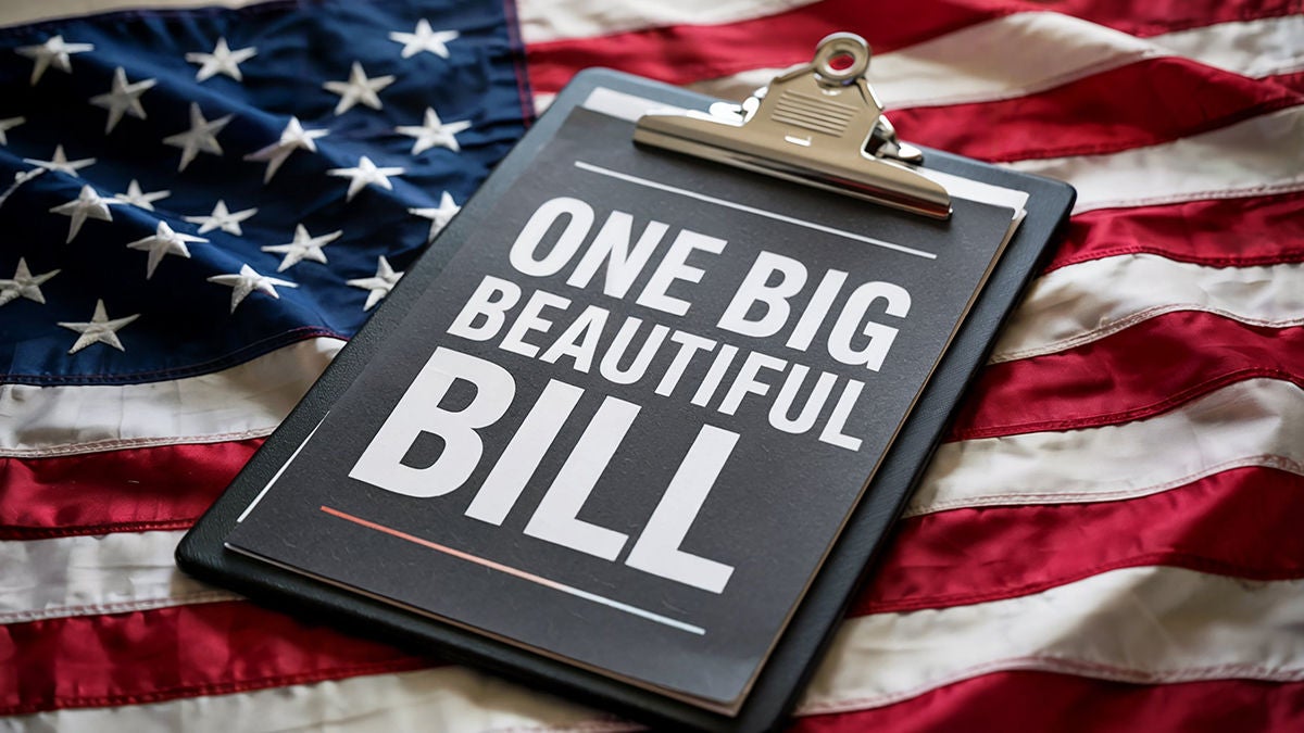 Clipboard with text one big beautiful bill rests on a rippling american flag
