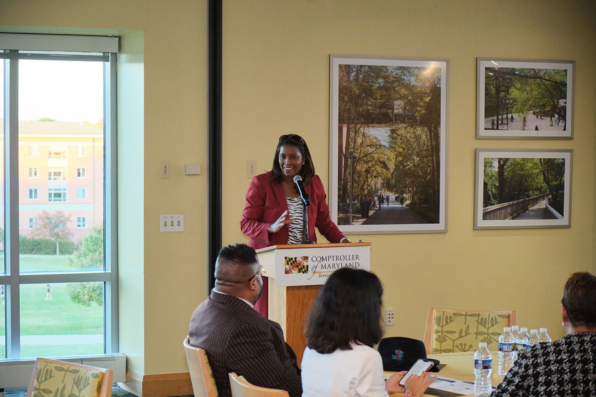 Woman standing at a podium speaking to a crowd